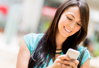 Woman with brown hair and blue shirt smiles down at her phone
