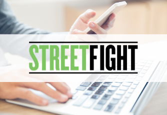 person typing on laptop and holding a phone, Streetfight graphic over top